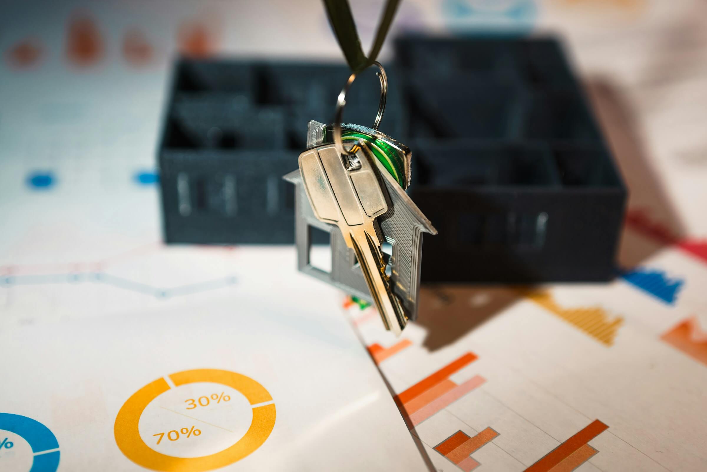 Property Search: House key with keychain placed on financial charts representing Florida real estate investment
