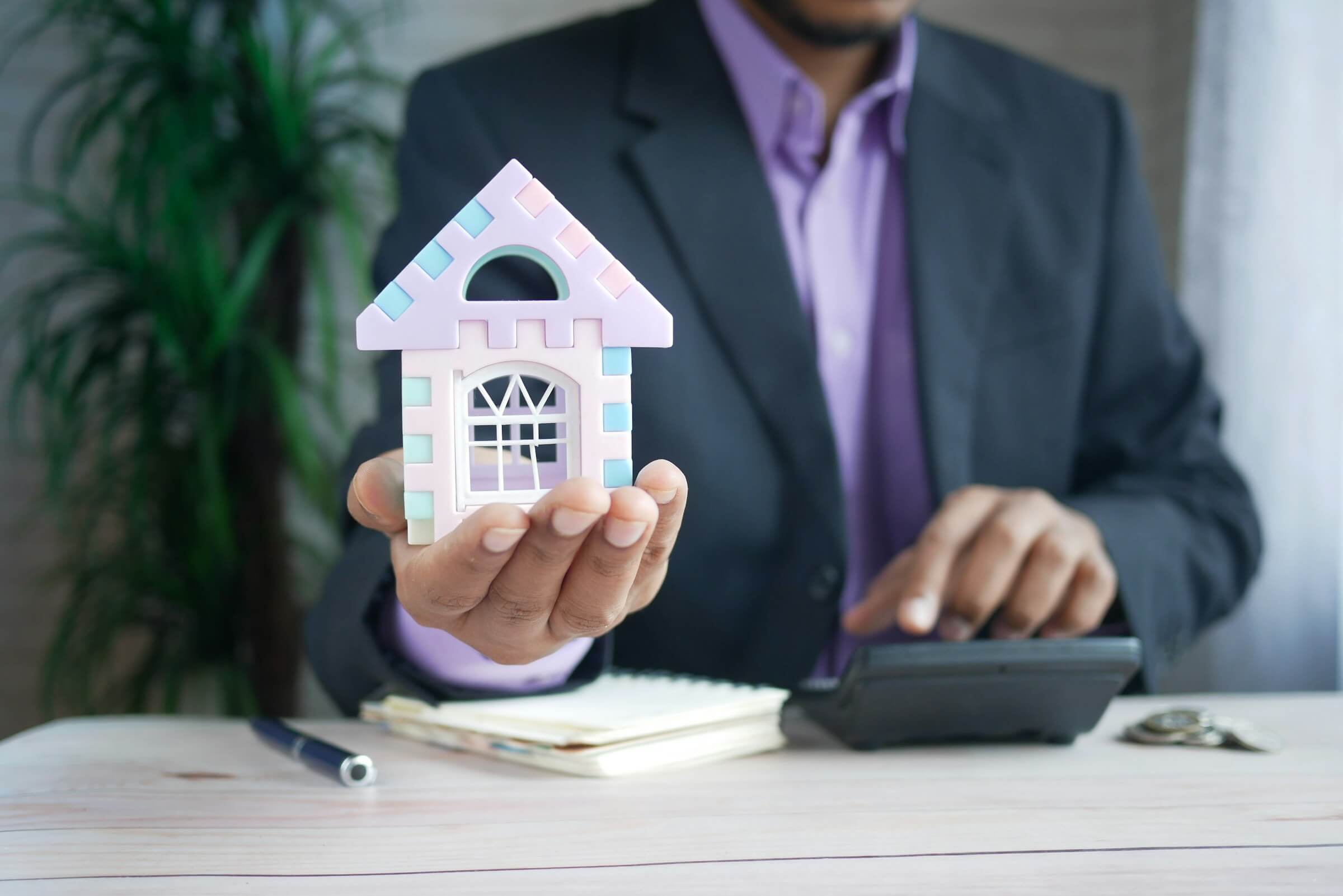 A realtor holding a model of a house; join US Prime Realty today!