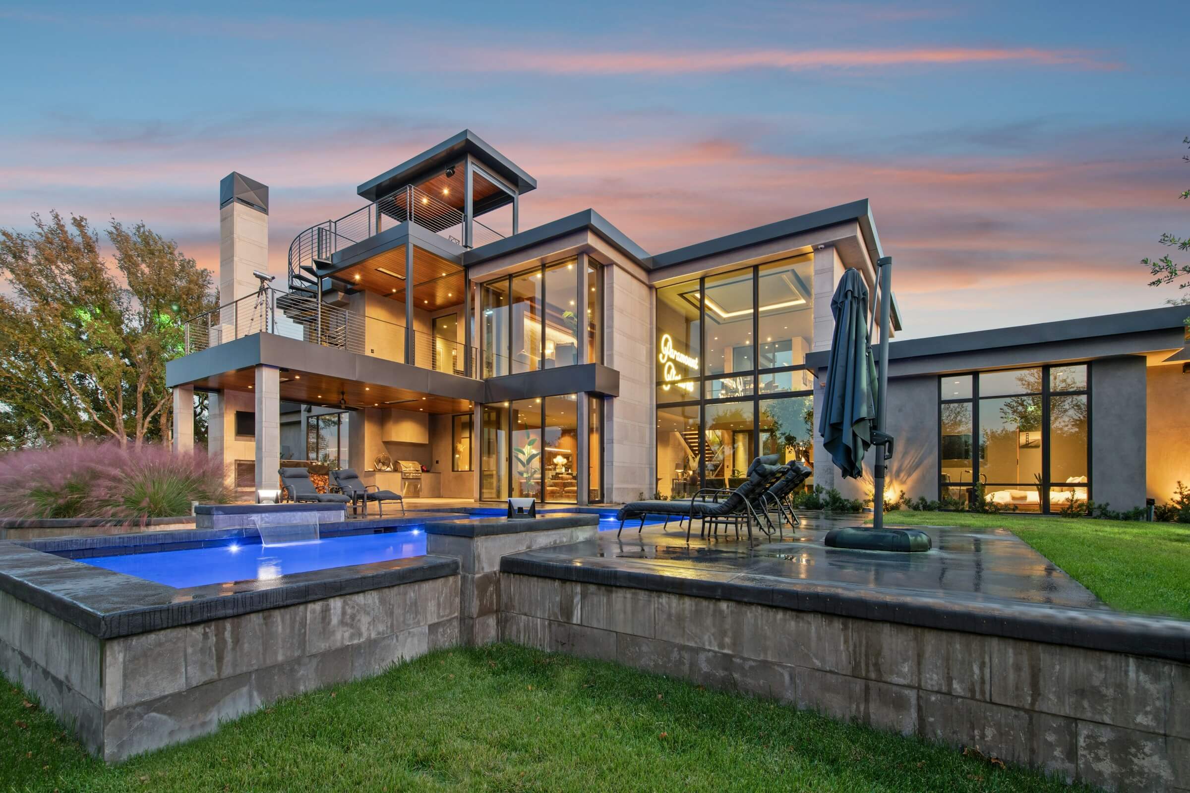 Modern luxury homes with floor-to-ceiling glass windows, outdoor pool, and contemporary design at sunset.