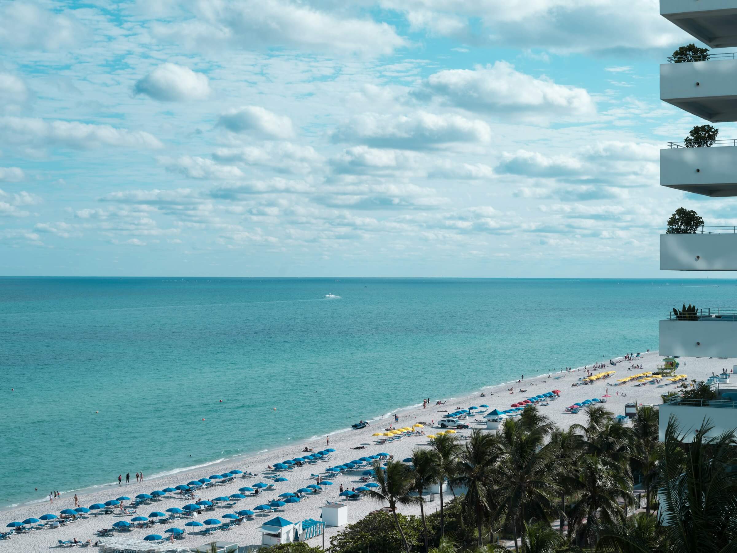 Beachfront view with turquoise ocean, white sand, and vacation condos overlooking the coast in Florida. Rent with US Prime Realty.