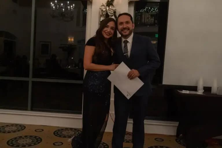 About 3 Real estate professionals posing with an award certificate at a formal event inside an elegant venue representing team success and client-focused service