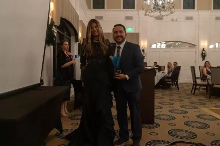 About 5 Real estate professionals at an awards event inside an elegant venue receiving recognition and celebrating achievements with clients and team members