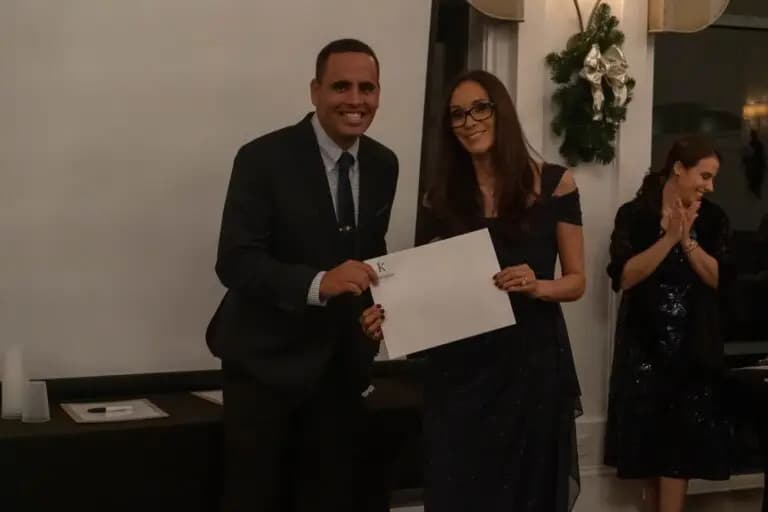 About 4 Real estate professionals receiving an award certificate during a formal event inside an elegant venue highlighting team achievements and client success