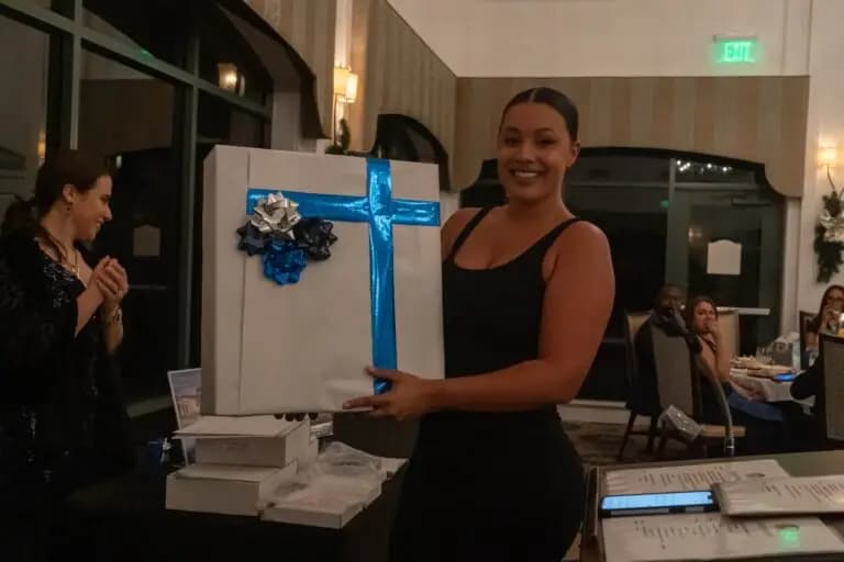 About 6 Holding a gift box at a real estate client appreciation event inside an elegant venue representing US Prime Realty community engagement and client relationships