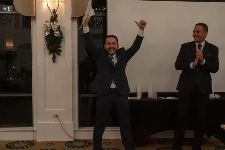 About 2 Real estate professionals celebrating at an awards event with applause and raised hands inside an elegant venue highlighting team success and achievements