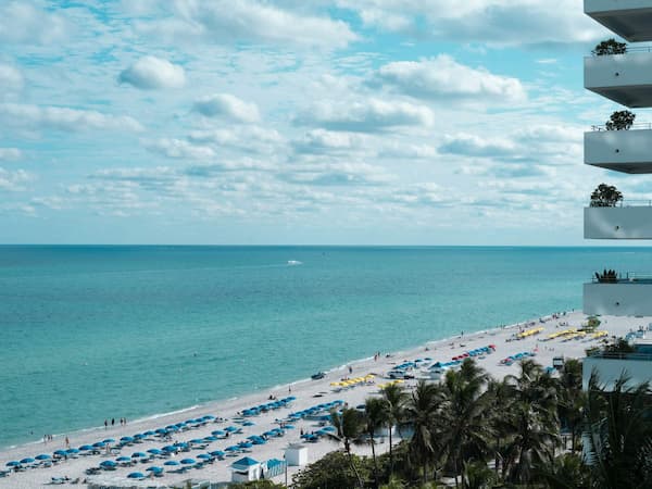Beachfront view with turquoise ocean, white sand, and vacation condos overlooking the coast in Florida. Rent with US Prime Realty.